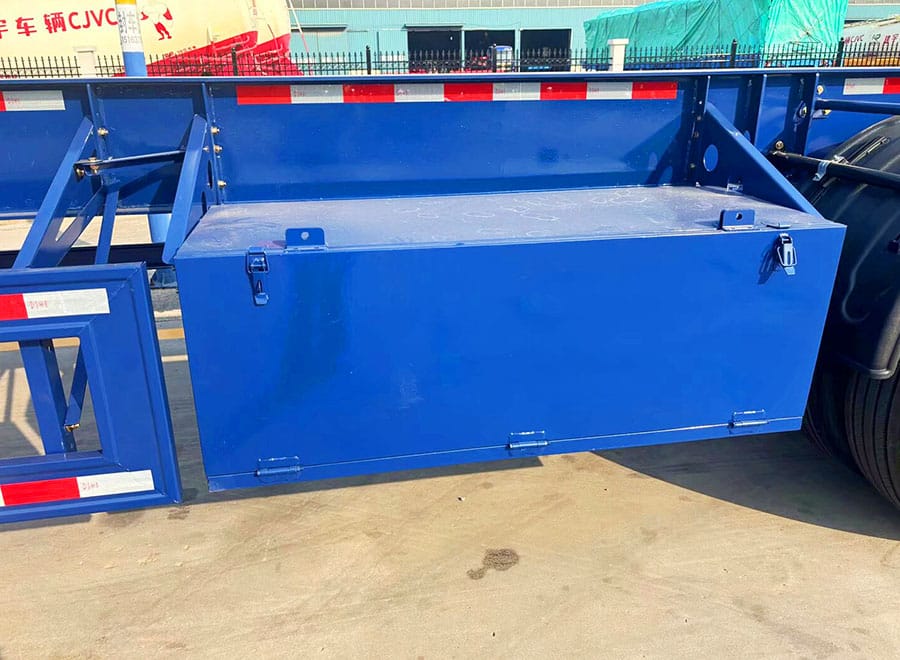 Blue toolbox mounted between the frame members and wheels of a container chassis