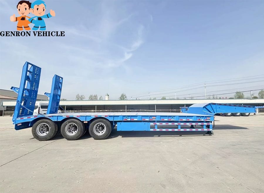 Side view of a blue low bed trailer and its rear ramps