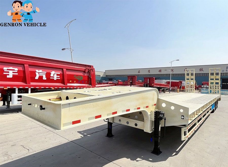 Cream-coloured low bed trailer with rear loading ramps in the factory yard