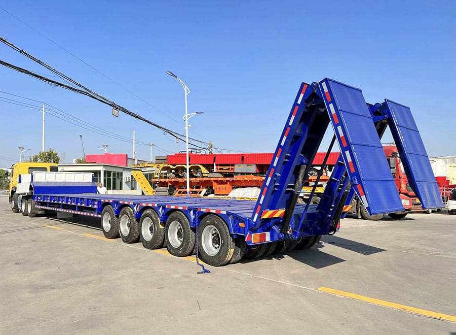 Blue low bed trailer viewed from the rear with loading ramps raised