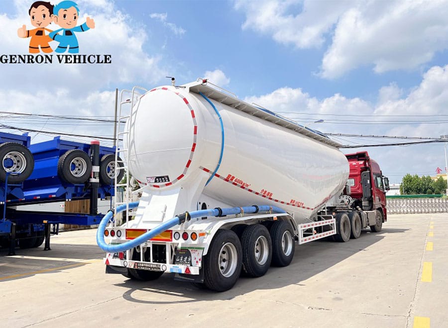 White bulk cement tanker coupled to a red tractor and viewed from the rear