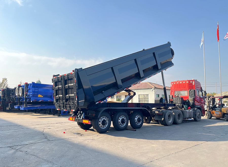 Rear dump semi trailer photographed in a yard with its body raised