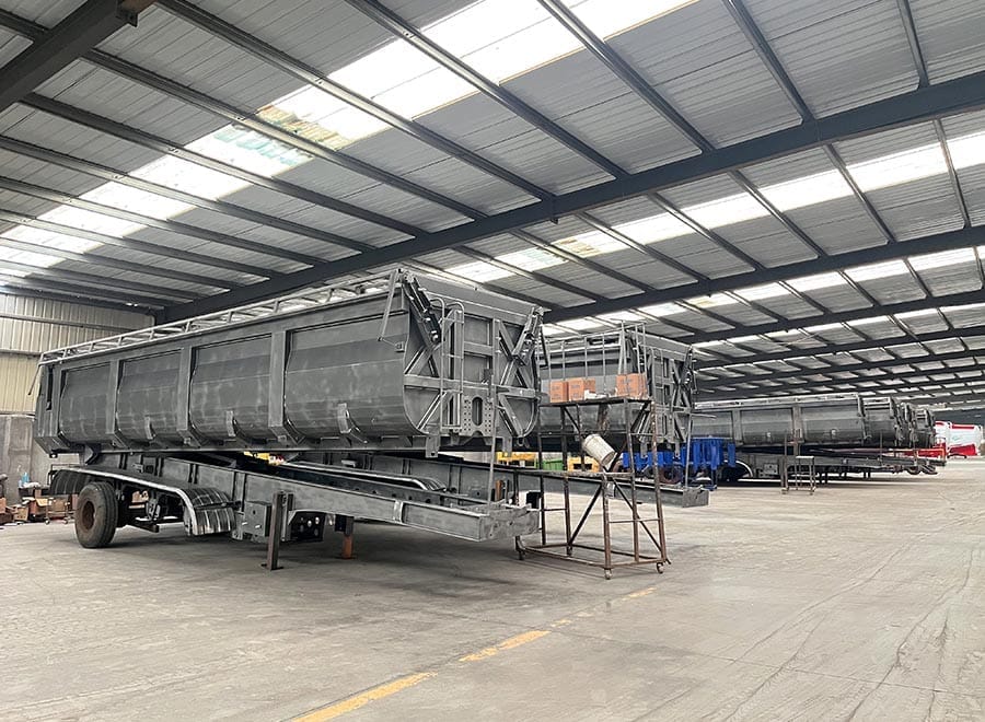 Unpainted rear dump trailer bodies in a fabrication workshop