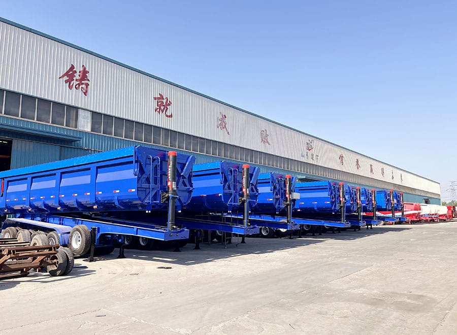 Blue rear dump trailers lined up outside the factory