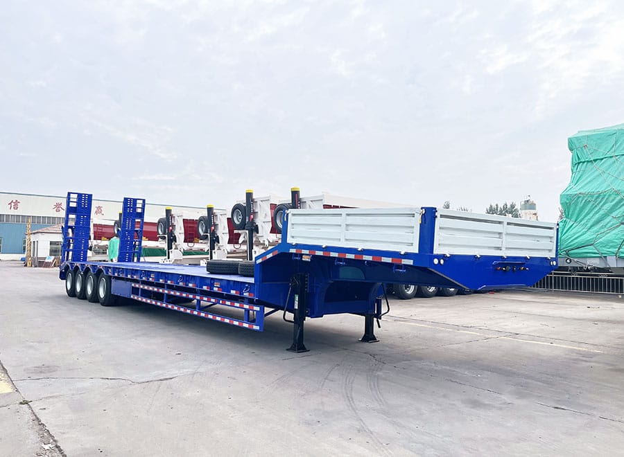 Blue low bed trailer with rear ramps and white gooseneck side panels