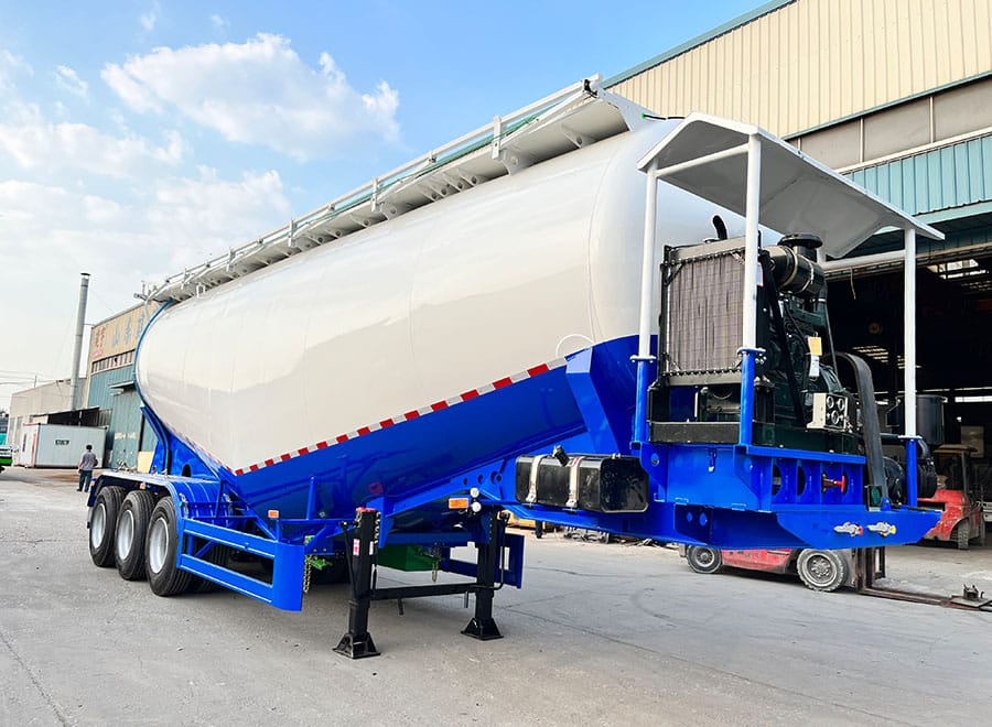 White and blue bulk powder tanker with equipment at the front