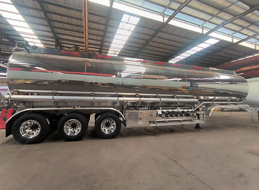 Polished metal tank trailer with side pipework inside the workshop