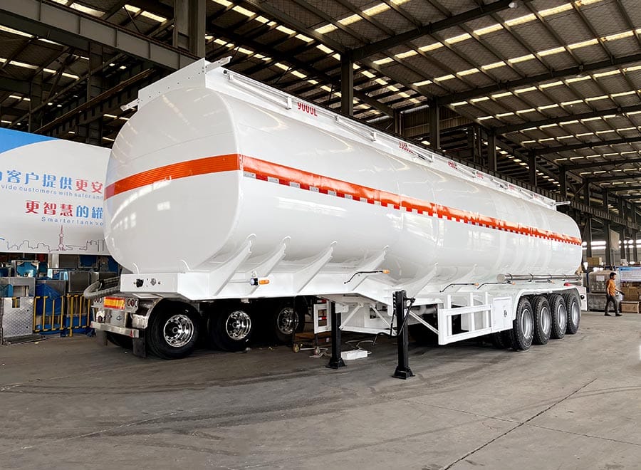White tanker trailer with an orange stripe inside a workshop