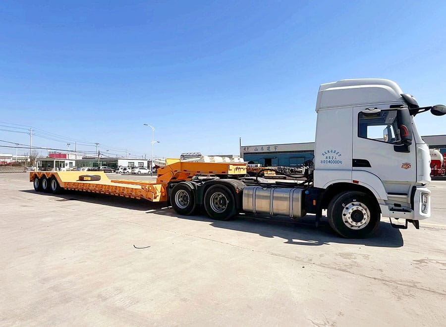Yellow GENRON removable gooseneck lowboy coupled to a tractor