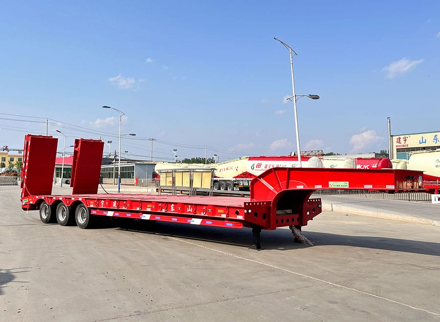 Red low bed semi trailer with a lowered deck and raised rear ramps