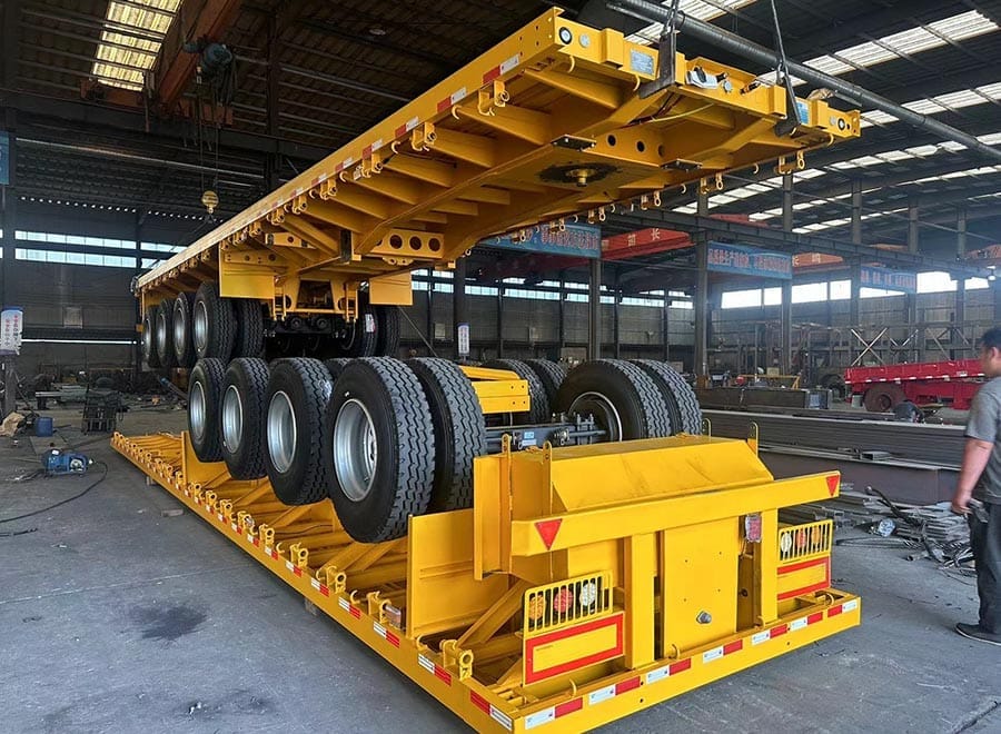 Yellow flatbed trailers stacked for shipment with cross-members visible