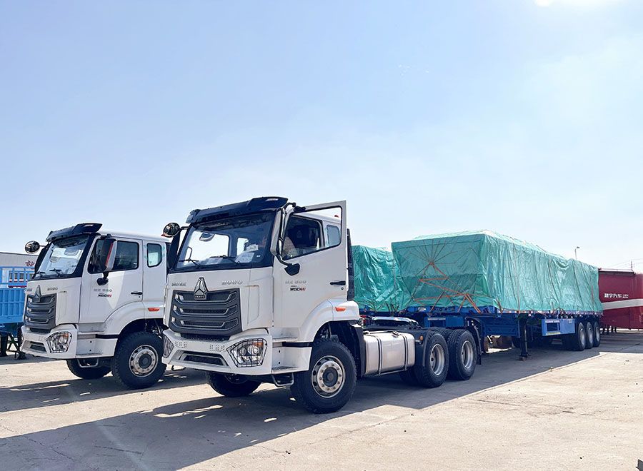 White HOWO tractor trucks with a covered trailer parked in the yard
