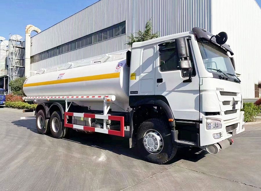 White cab tanker truck parked beside a workshop