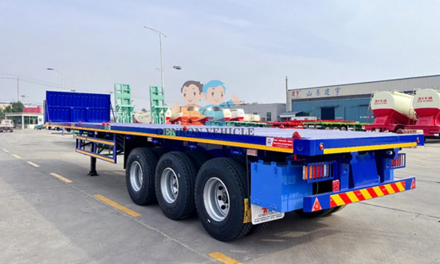 Rear-quarter view of a blue GENRON flatbed trailer in the yard