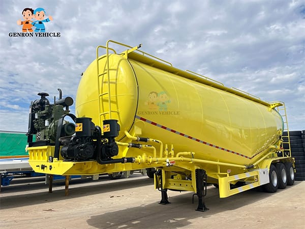 Opposite front view of a yellow bulk cement tanker and pipework